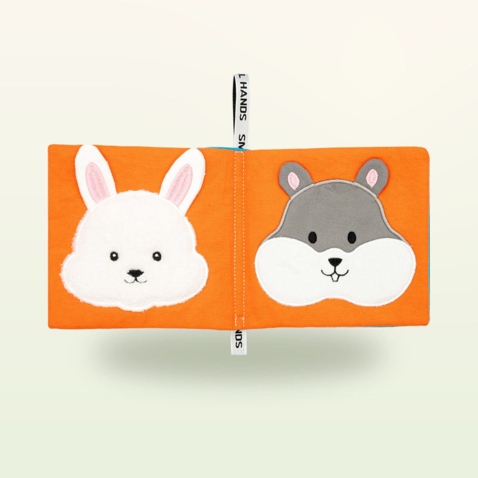 Small Hands Haustiere Montessori Stoffbuch aufgeschlagen – weißer Hase und grauer Hamster auf sanftem Creme-Hintergrund – ab 0 Monaten
