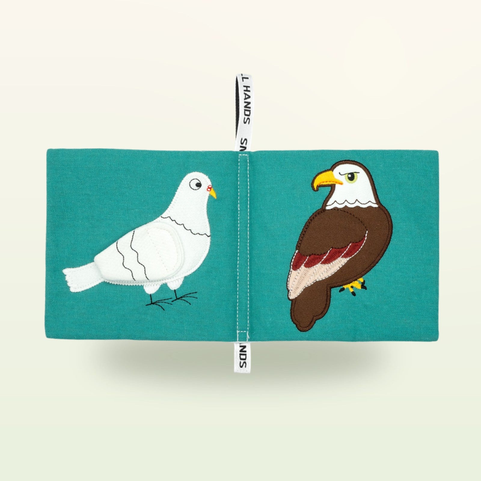Small Hands Vögel Montessori Stoffbuch aufgeschlagen – weiße Taube und Weißkopfseeadler auf sanftem Creme-Hintergrund – ab 0 Monaten