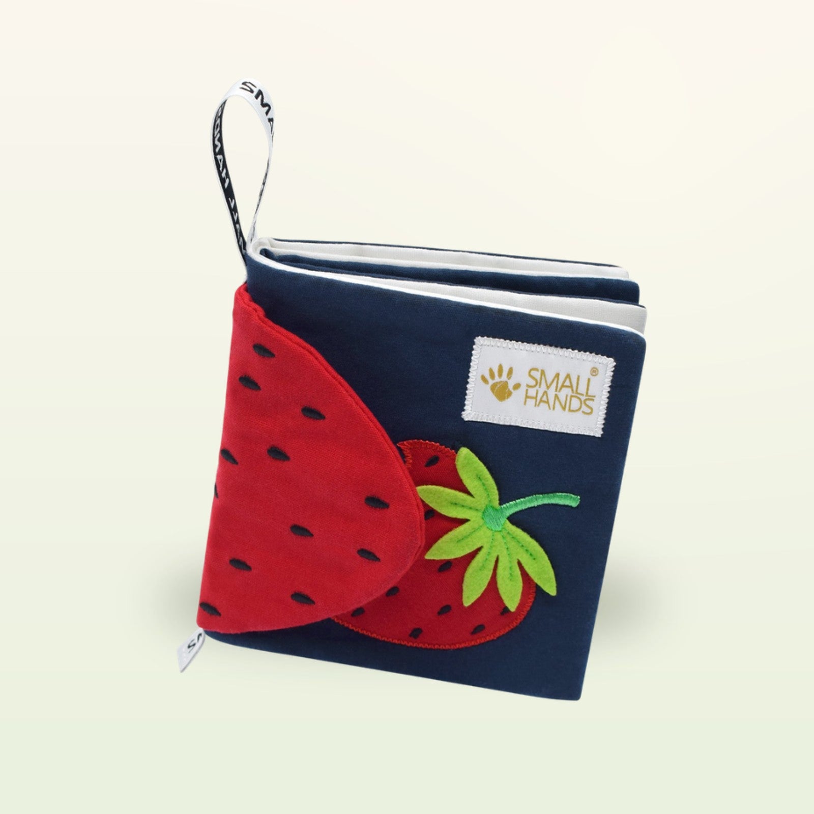Small Hands Bunte Früchte Montessori Stoffbuch aufrecht stehend mit roter Erdbeere auf sanftem Creme-Hintergrund – ab 0 Monaten