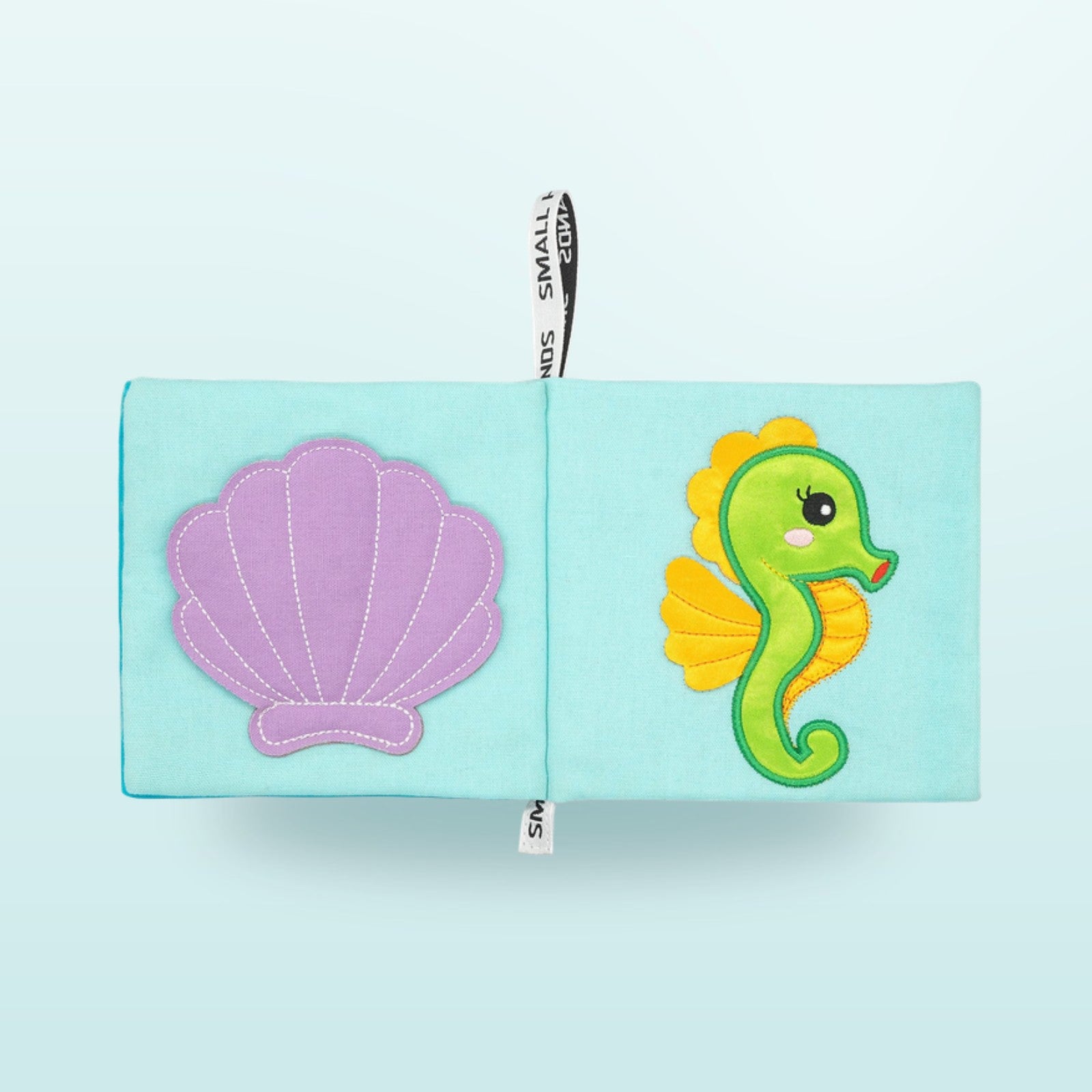 Small Hands Meeresbewohner Montessori Stoffbuch Doppelseite mit Muschel und Seepferdchen auf sanftem Unterwasser-Blau-Hintergrund – ab 1 Jahr