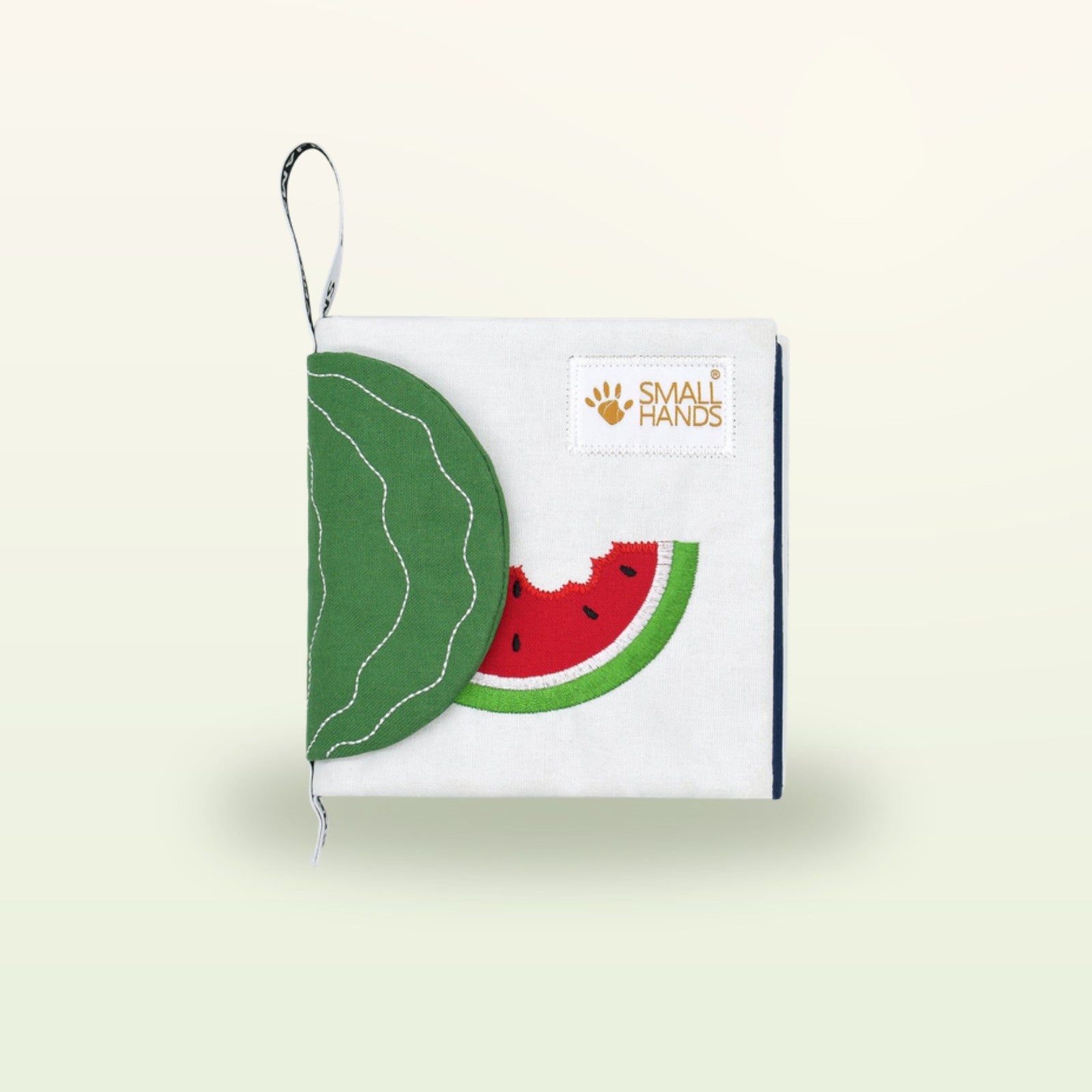 Small Hands Exotische Früchte Montessori Stoffbuch geschlossen mit Wassermelone und Blatt-Flap auf sanftem Creme-Hintergrund – ab 0 Monaten